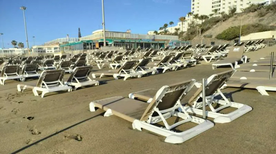 Het zand blijft de ligbedden op het strand van Playa del Inglés begraven