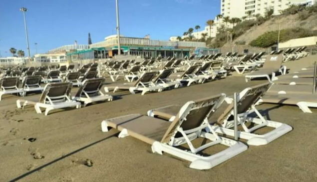 Het zand blijft de ligbedden op het strand van Playa del Inglés begraven